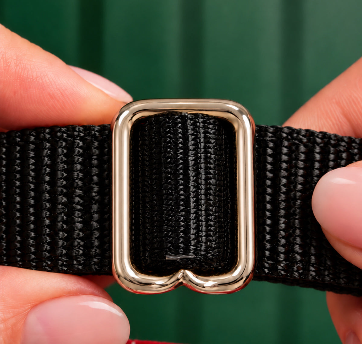 Hands holding the metal adjuster slider on the black collar strap